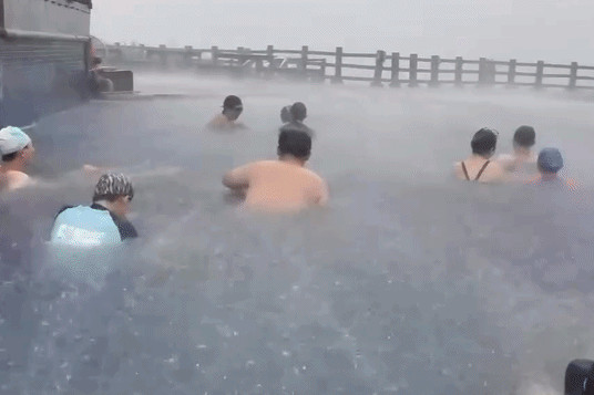 Khách ngâm suối nước nóng bất chấp mưa lớn, gió quật mạnh ở Trung Quốc